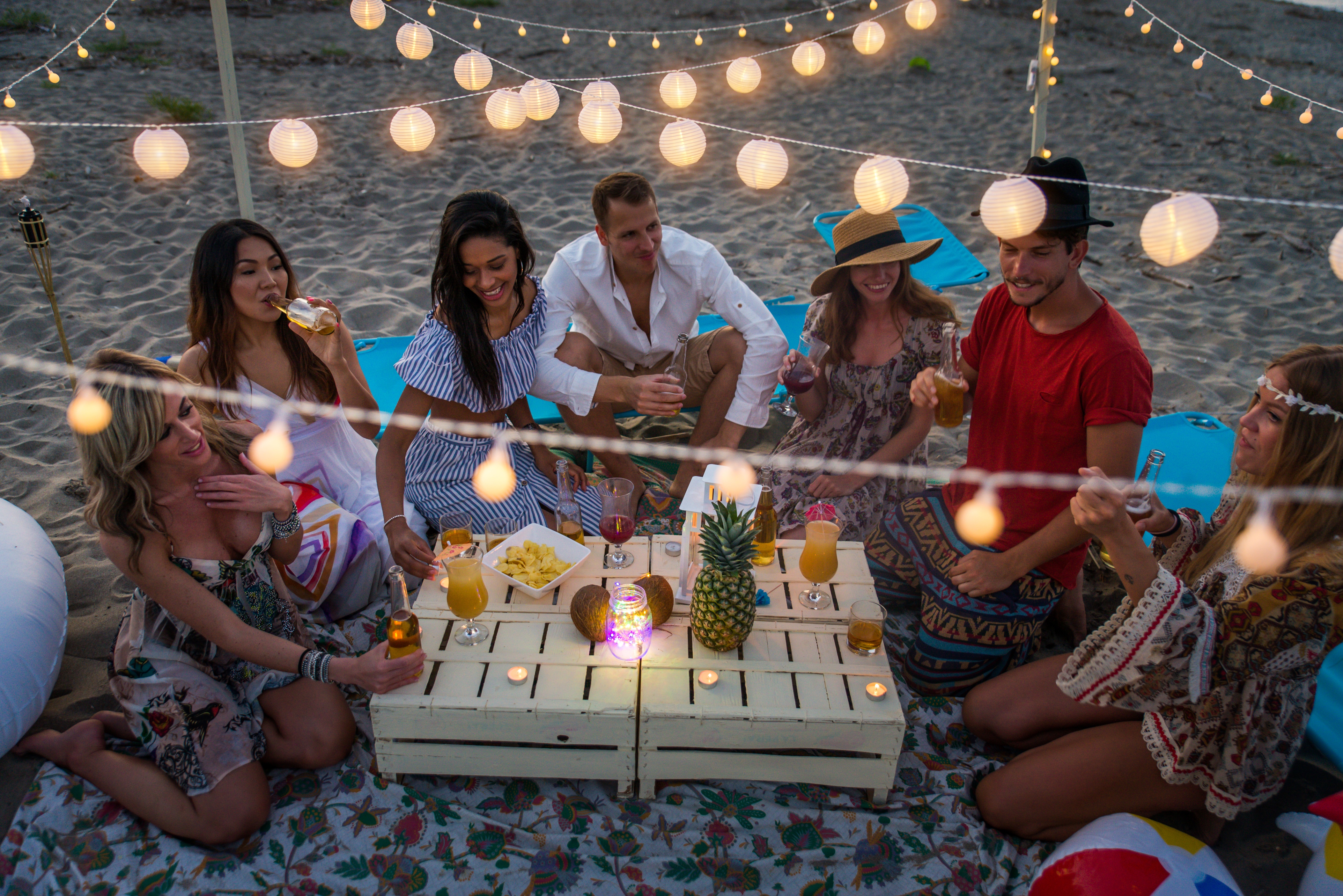 Group of friends sitting together outside with a variety of drinks in hand, smiling together.