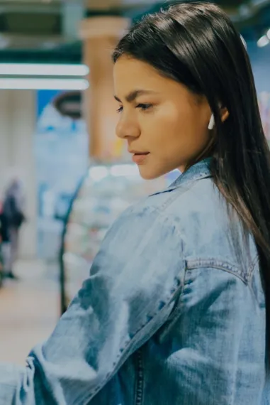 Young woman examines alcoholic beverage in the isle of a retail store.