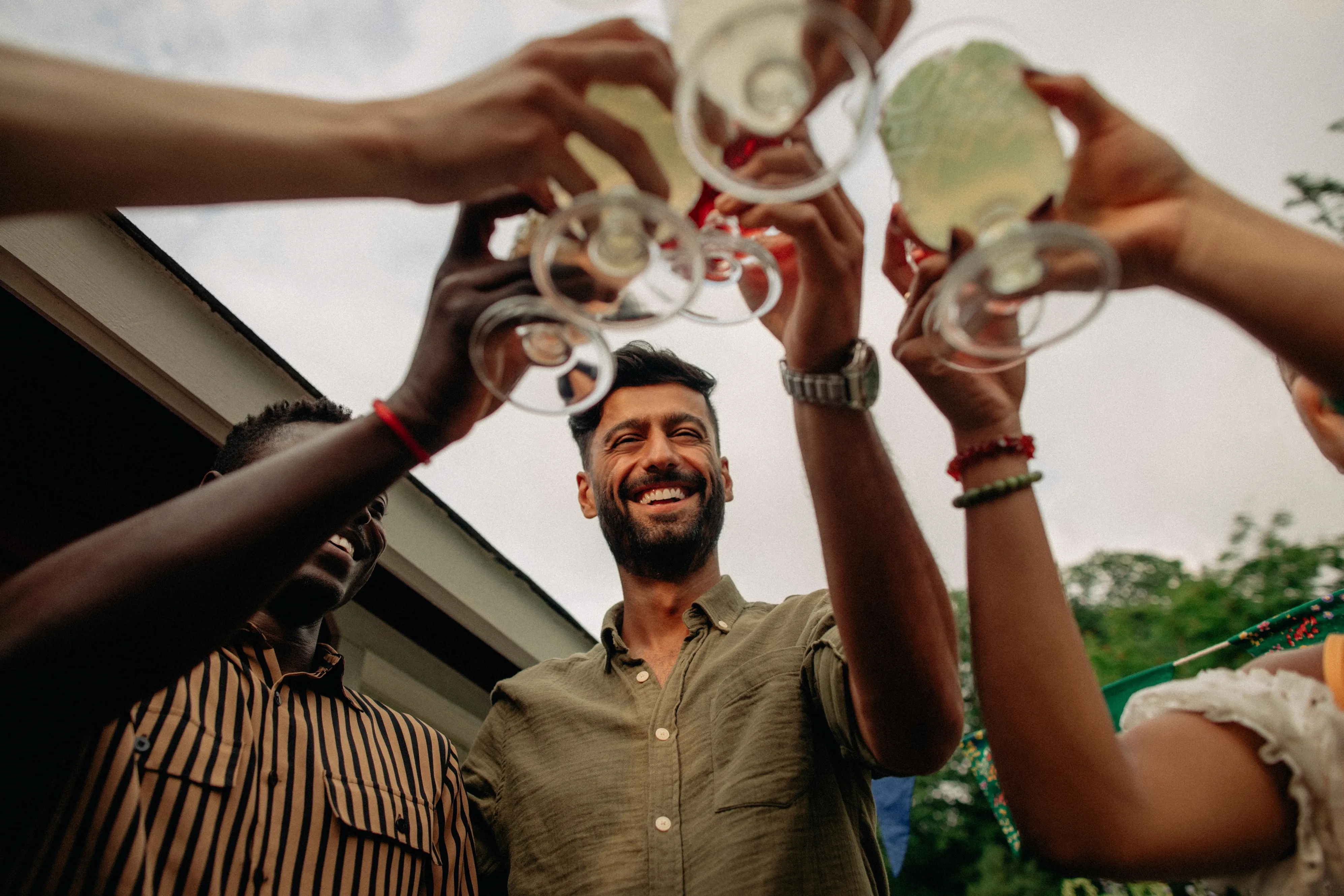 Low angle view of happy friends toasting drinks at a party.