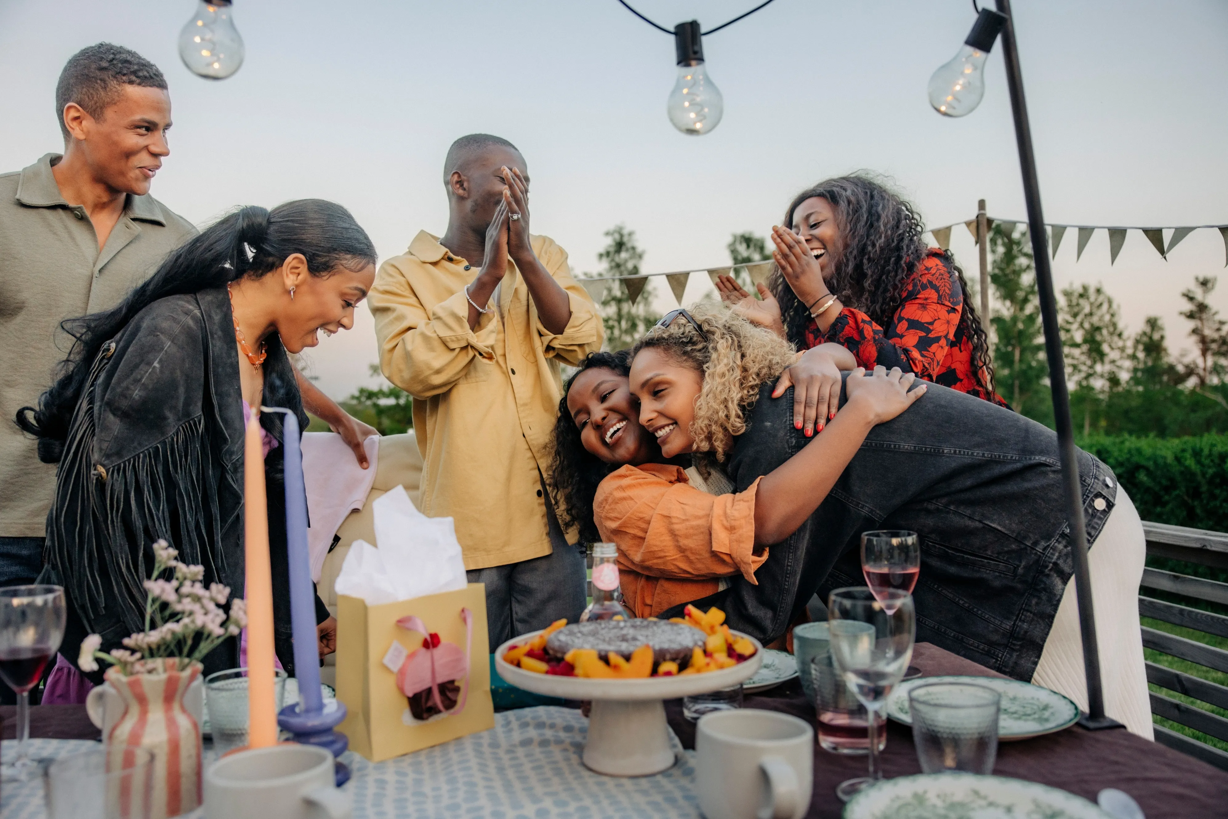Smiling young woman embracing her friend during a birthday celebration.